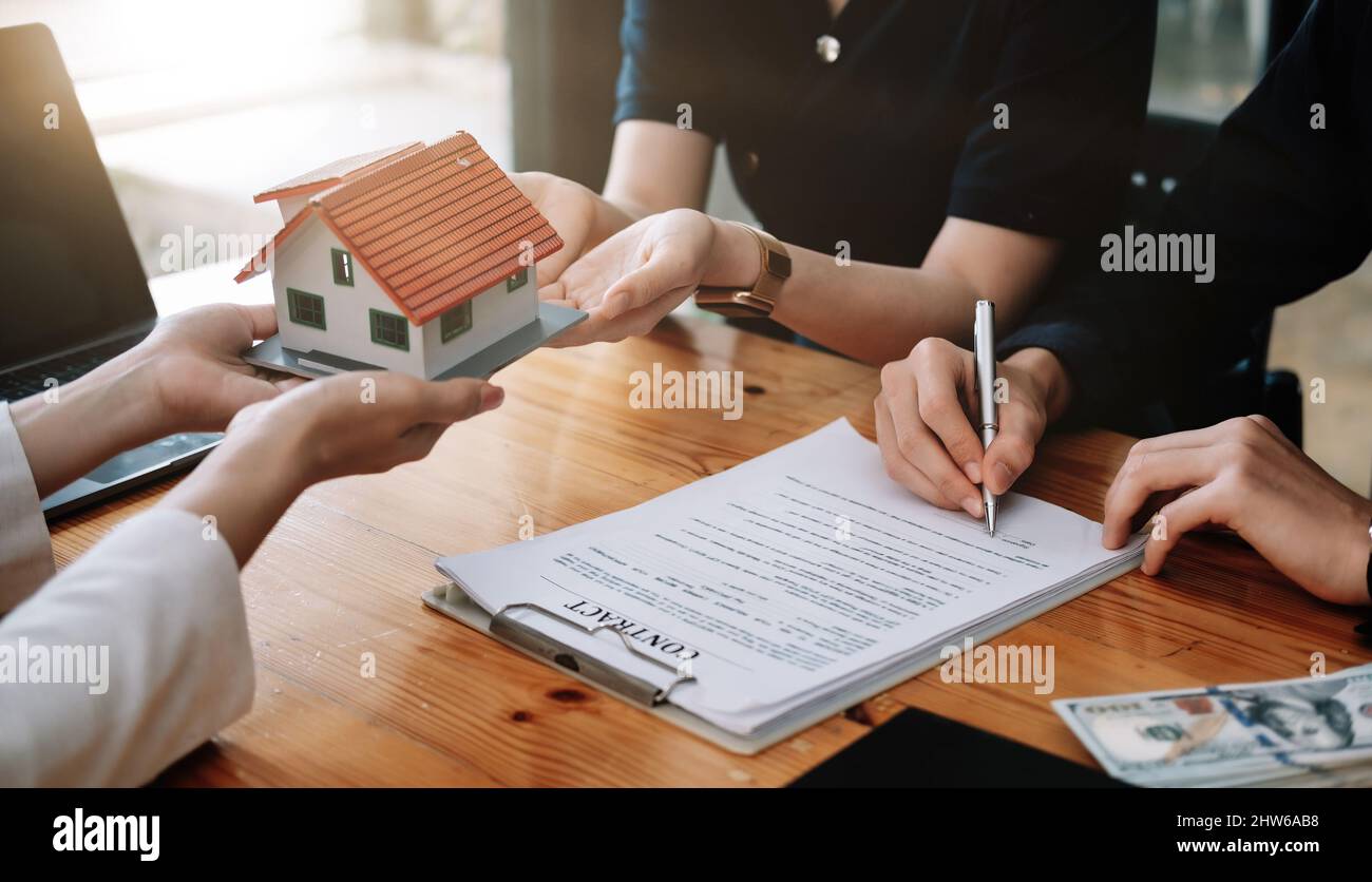 Immobilienmakler bieten Hand für Kunden unterzeichnen Vertrag Unterzeichnung für Kauf oder Verkauf Haus. Happy Asian paar Unterzeichnung eines Vertrags zusammen bei Stockfoto