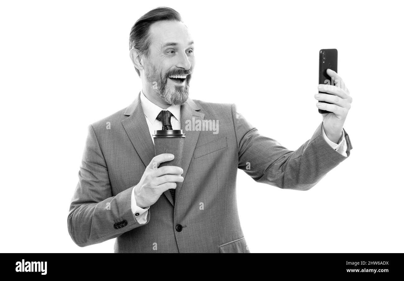 Glücklicher Mann Blogger in Anzug meking Selfie am Telefon und trinken Kaffee isoliert auf weiß, Videoanruf. Stockfoto