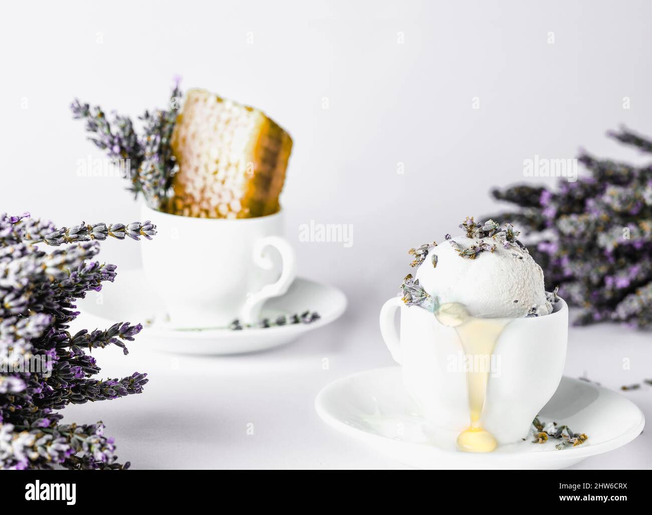 Eis in einer Kaffeetasse mit Lavendelblüten auf weißem Hintergrund Stockfoto