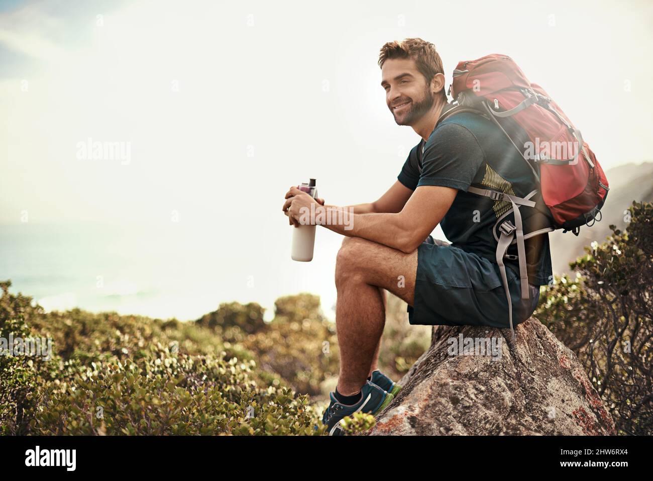 Der perfekte Tag, um in der Natur zu sein Aufnahme eines jungen Mannes, der beim Wandern eine Wasserpause einnahm. Stockfoto