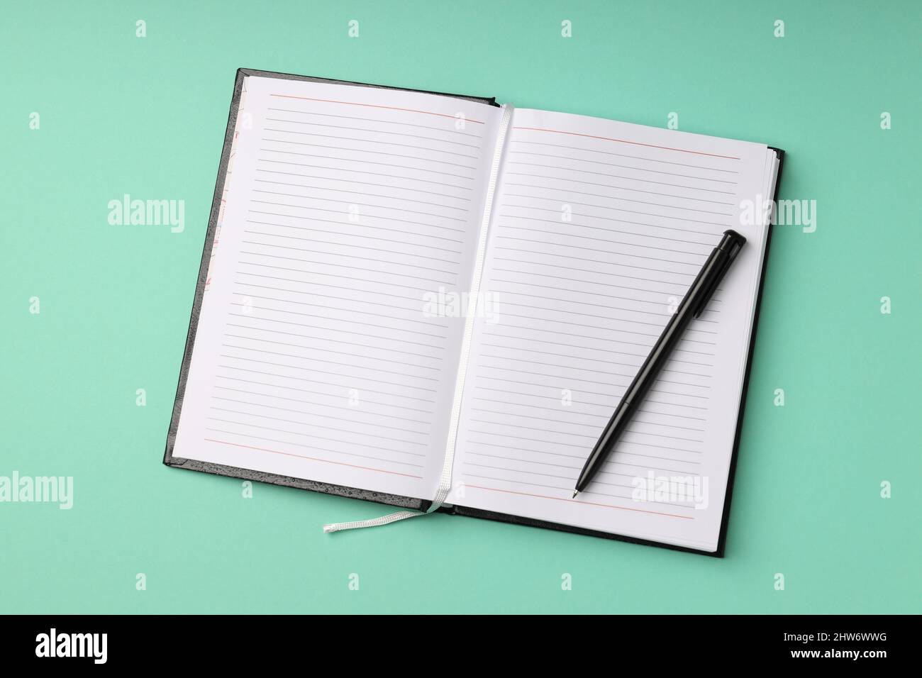 Leeres Notizbuch mit Stift auf mintgrün Hintergrund Stockfoto