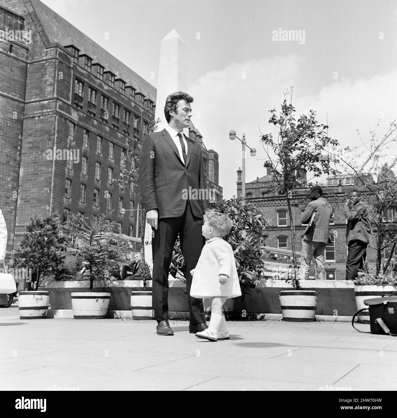 6ft 3 Clint Eastwood, abgebildet auf dem St. Peter's Square, Manchester, mit Antony Rixon, 18 Monate alt. Antony ist 32 cm groß. 12.. Juni 1967. Stockfoto