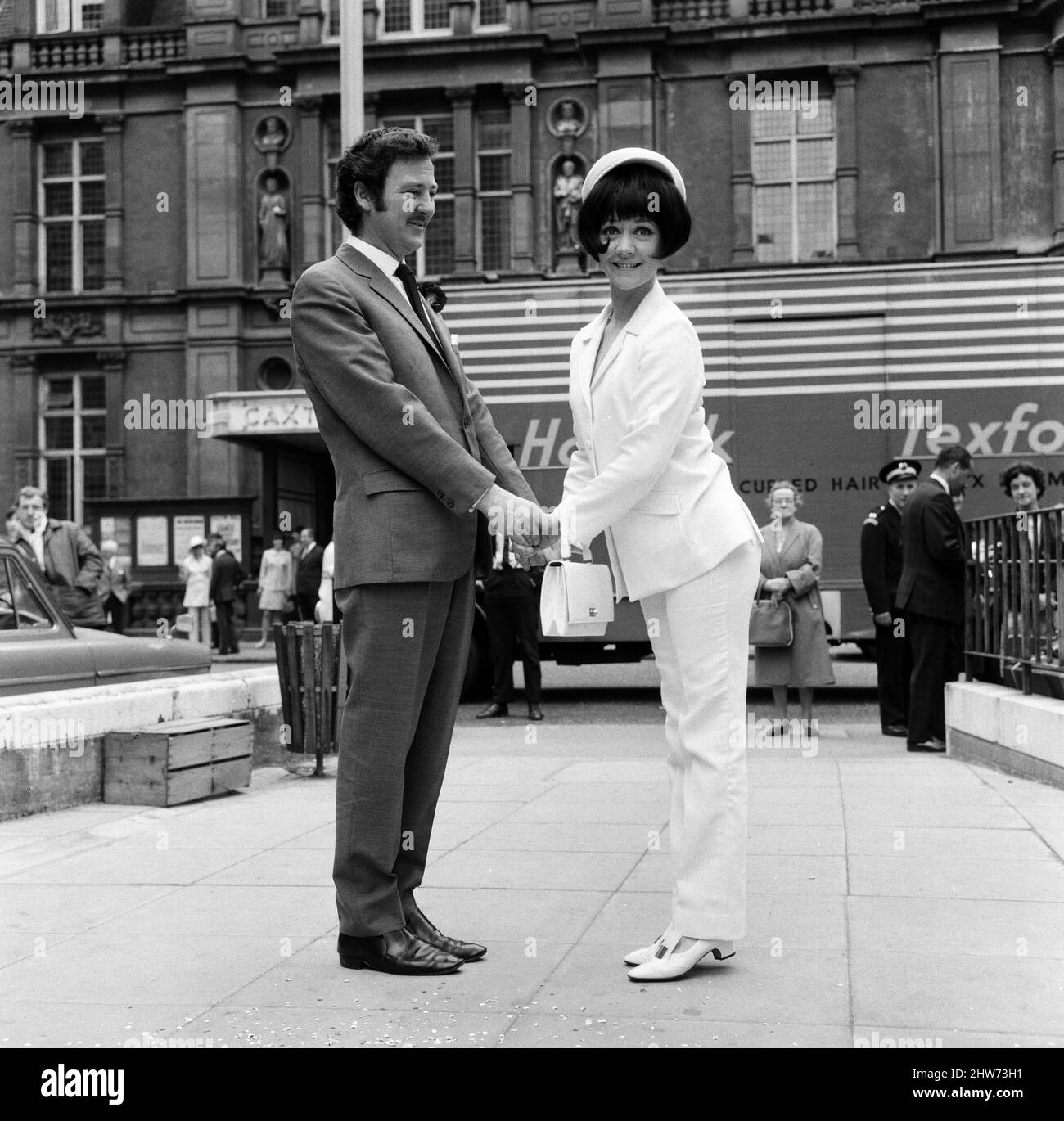 Als der Schauspieler Robin Hunter heute in der Caxton Hall heiratete, trug seine Schauspielerin Braut Amanda Barrie ebenfalls einen Anzug. Ihre war in weißem Leinen mit einem weißen passenden Hut. Amanda sagte scherzhaft: „Aber Robin wird die Hose in unserer Ehe tragen.“ 19.. Juni 1967. Stockfoto