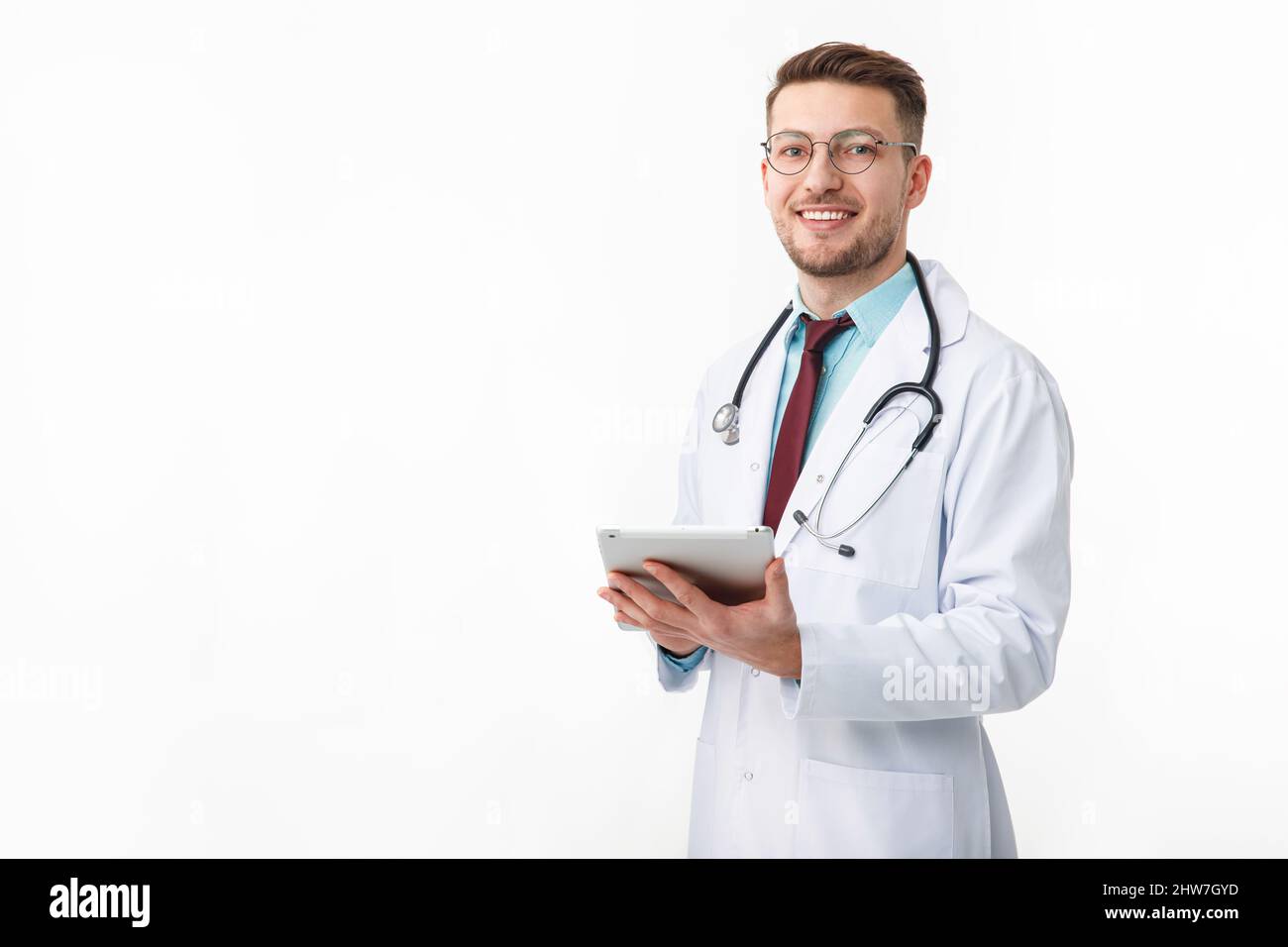 Porträt eines selbstbewussten jungen Arztes auf weißem Hintergrund. Hält eine Tablette in den Händen Stockfoto
