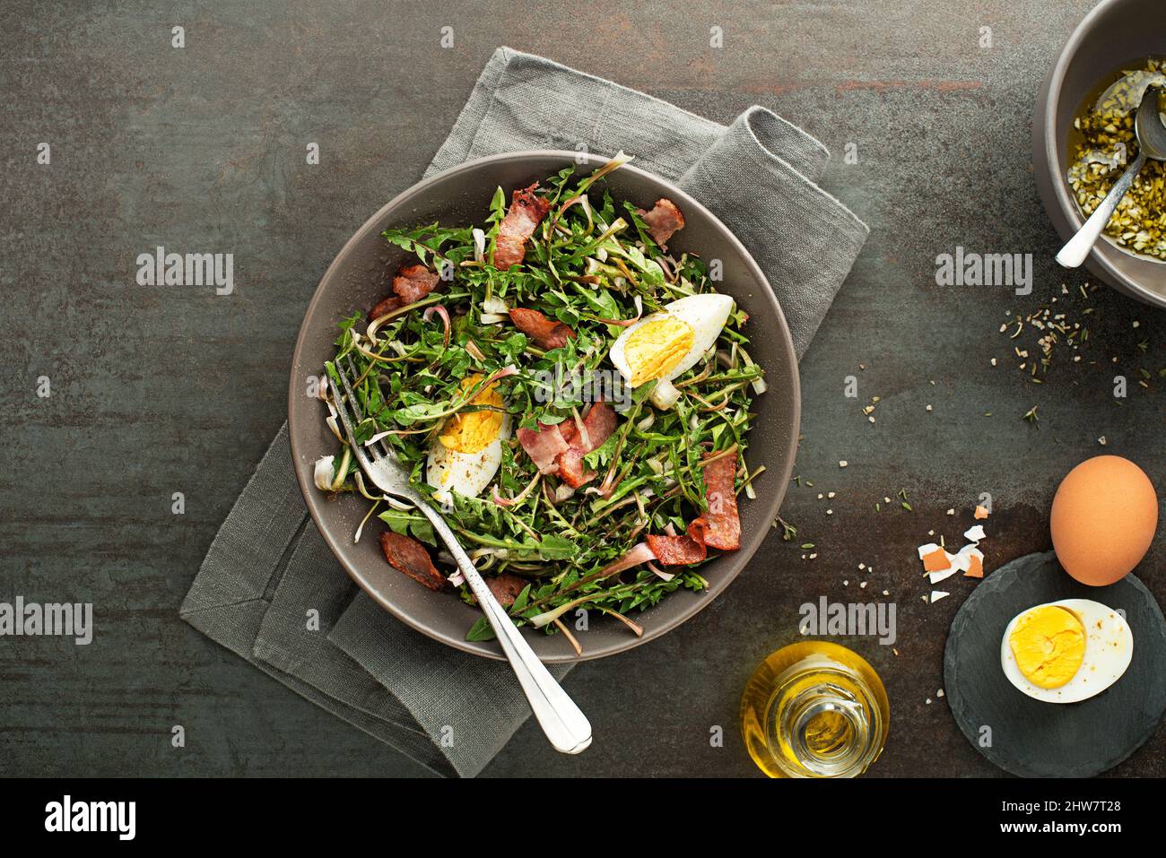 Frischer Dandelion-Salat mit Speck und Eiern auf grauem Hintergrund Stockfoto