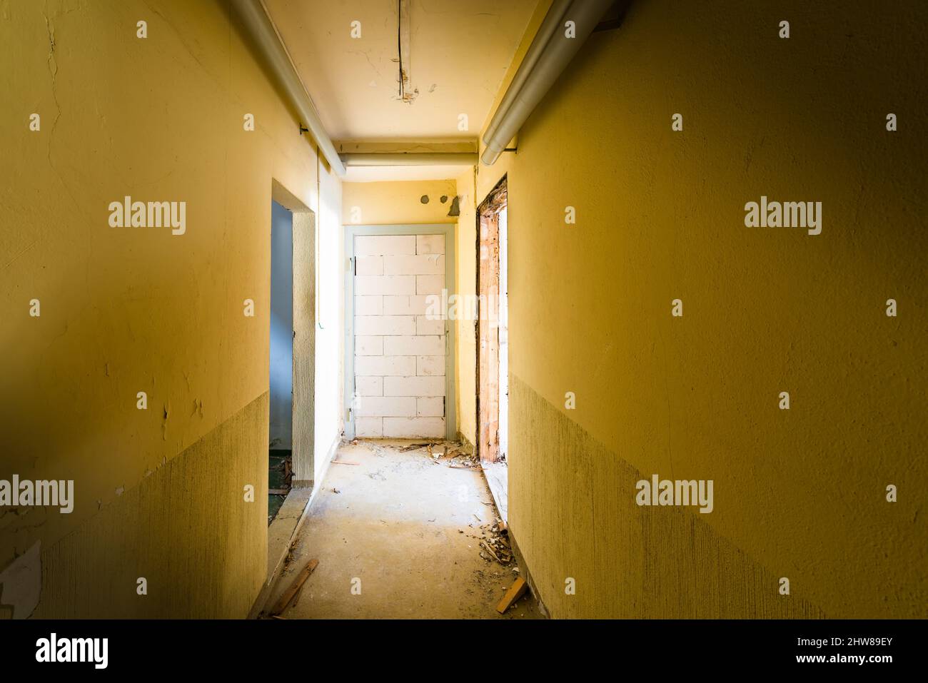 Korridor in einem zerstörten Haus. Backstein mit Türwänden. Das Konzept des „Aushaltens aus einer schwierigen Situation“ Stockfoto