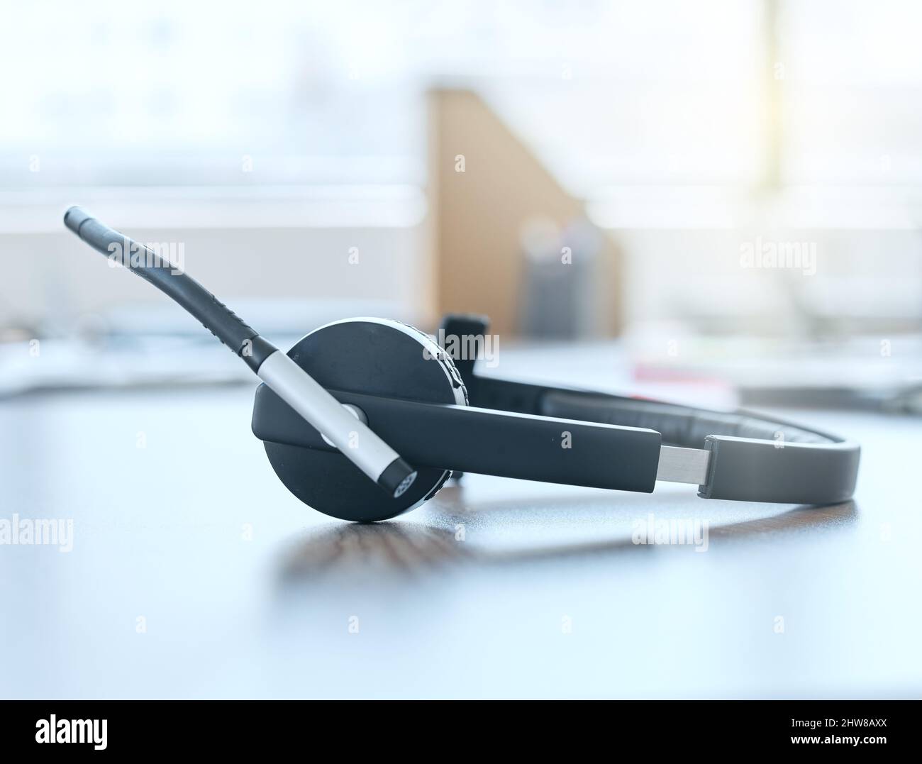 Bereit, Ihren Anruf anzunehmen. Aufnahme eines Headsets, das tagsüber in einem leeren Büro auf einem Schreibtisch liegt. Stockfoto