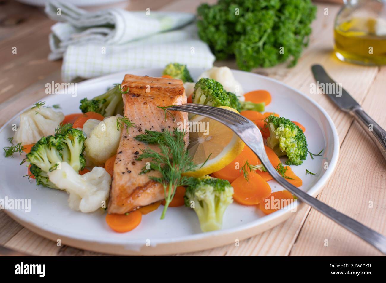 Gesundes Fischgericht mit gebratenem Lachsfilet, serviert mit kaiserlichem Gemüse wie Brokkoli, Blumenkohl und Karotten auf einem Teller. Low Carb Abendessen Stockfoto