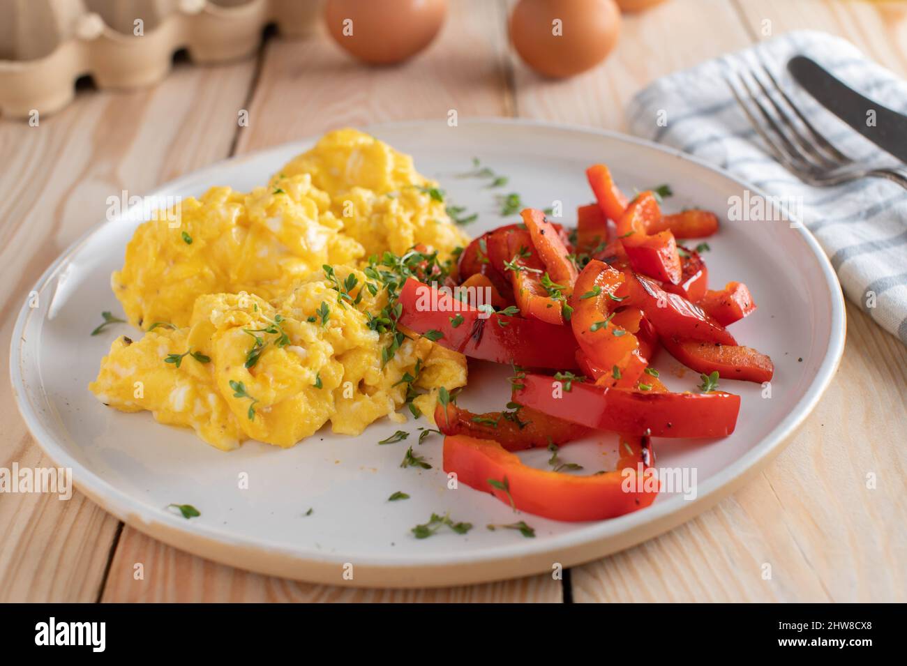 Scrambeld-Eier mit geröstetem roten Paprikasalat. Gesunder kohlenhydratarger oder ketogener Frühstücksteller Stockfoto