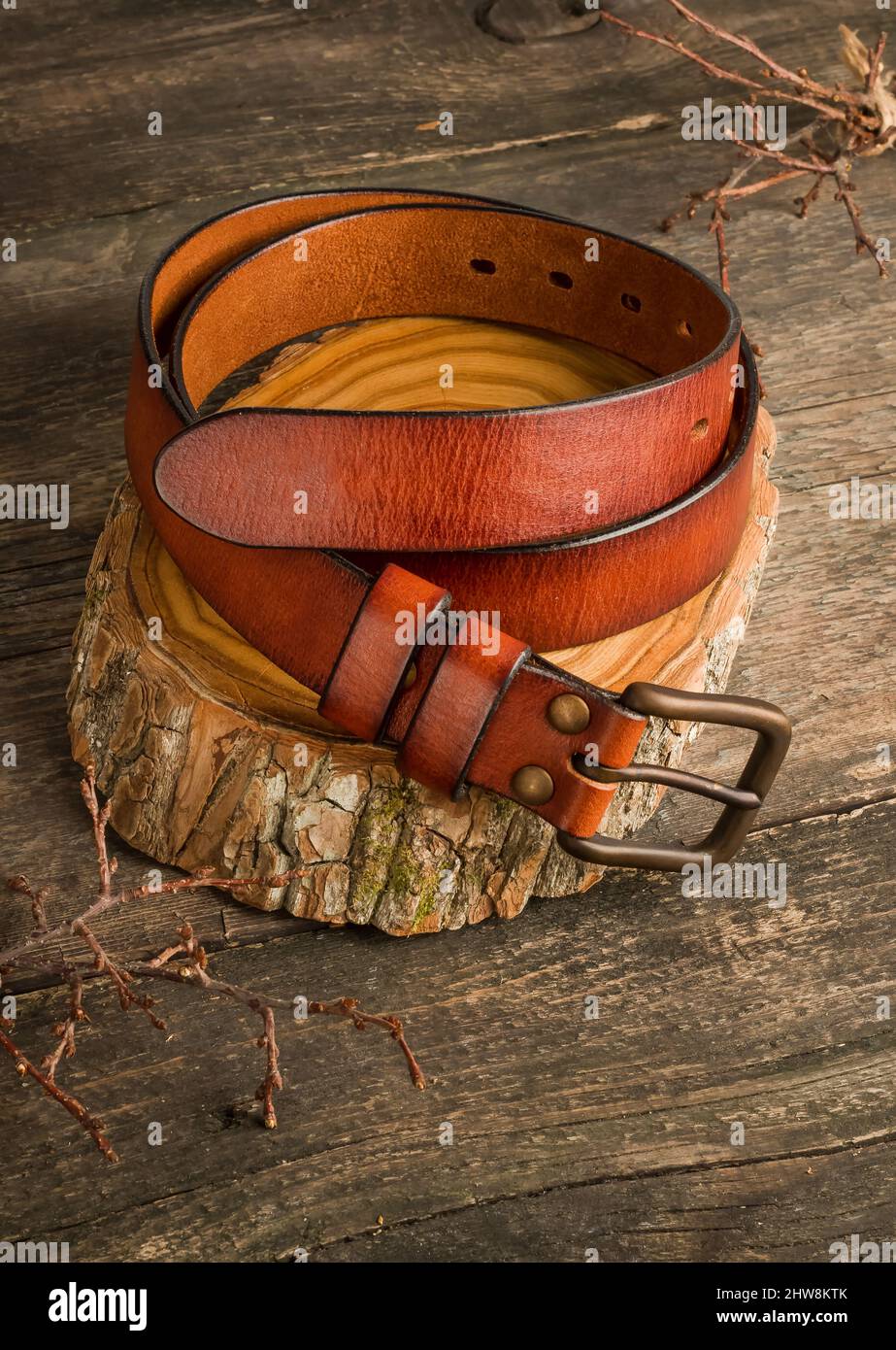 Männer-Leder-Hosengürtel in braun-oranger Farbe auf einem alten Vintage-Holzhintergrund. Stockfoto