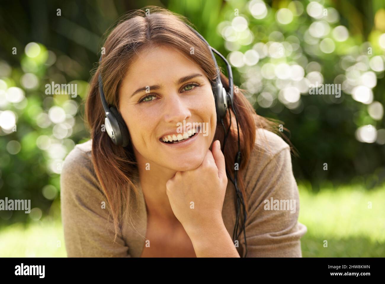 Genießen Sie die Symphonie der Natur. Aufnahme einer wunderschönen jungen Frau, die im Freien liegt und Musik hört. Stockfoto