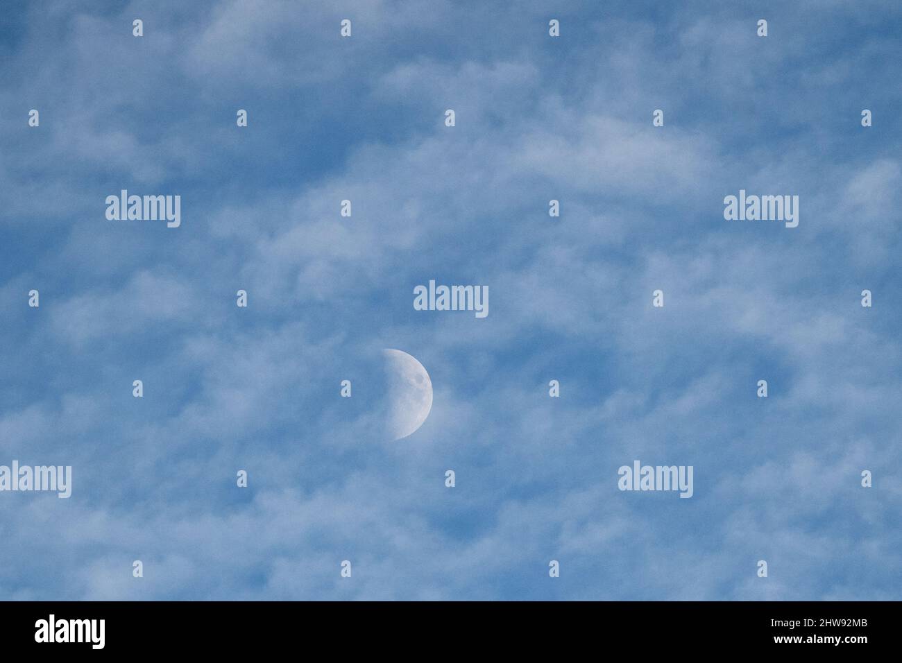 Halbmond sichtbar am blauen Himmel mit weißen Wolken Stockfoto