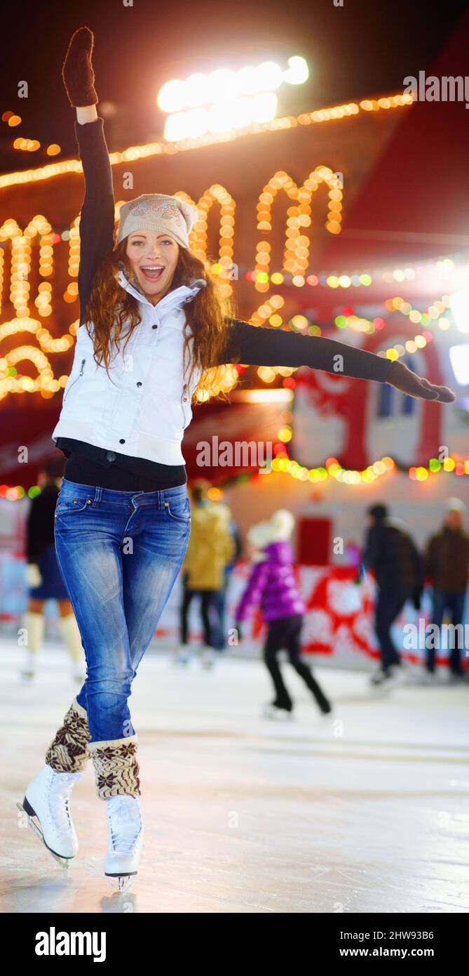 Shes Königin der Eisbahn. Aufnahme einer schönen jungen Frau, die nachts auf einer Eisbahn Schlittschuh führt. Stockfoto