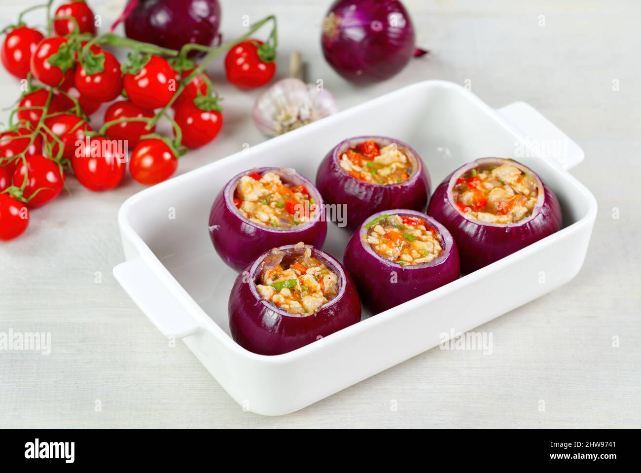 Rezept für gefüllte Zwiebeln. Rote Zwiebeln gefüllt mit Fleisch und Gemüse  in einer weißen Schüssel bereit, im Ofen zu backen Stockfotografie - Alamy