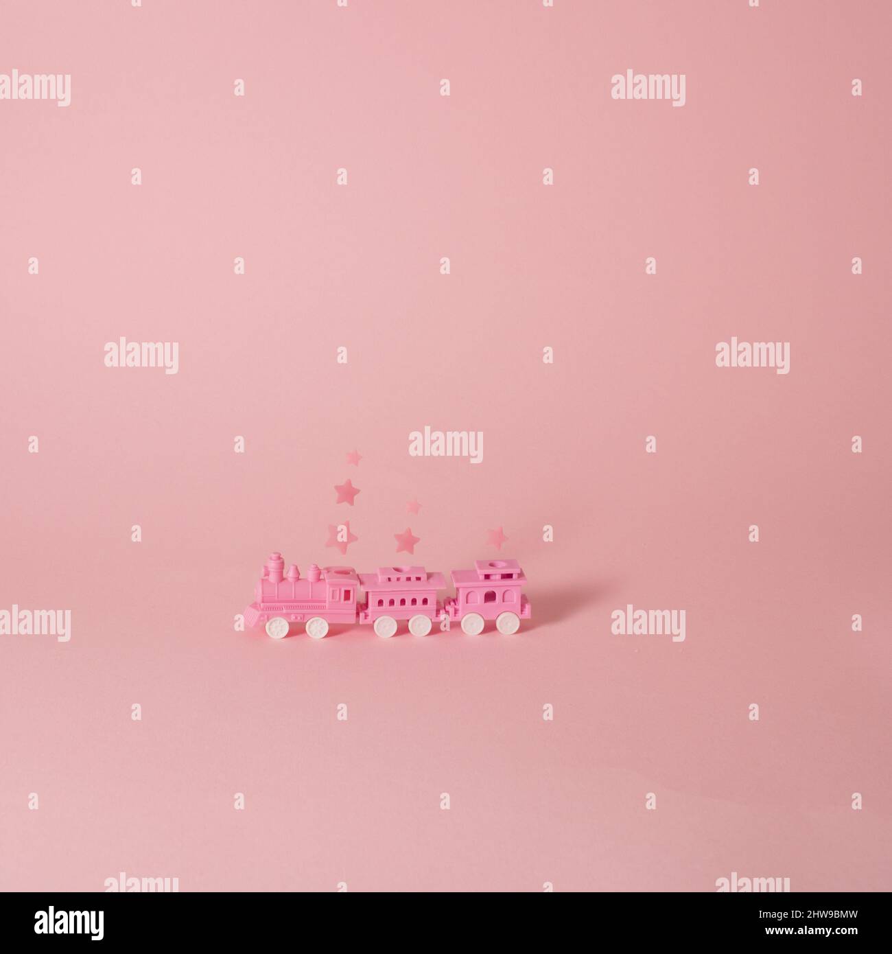 Magisch rosa Zug mit Waggons und Sternrauch auf pastellfarbenem Hintergrund Stockfoto