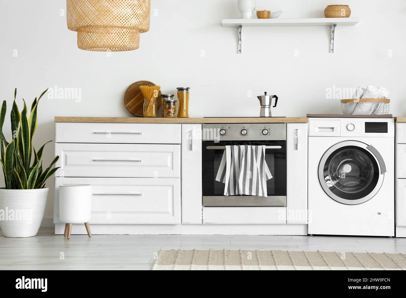 Innenraum der hellen Küche mit Waschmaschine, Backofen und weißer Theke  Stockfotografie - Alamy