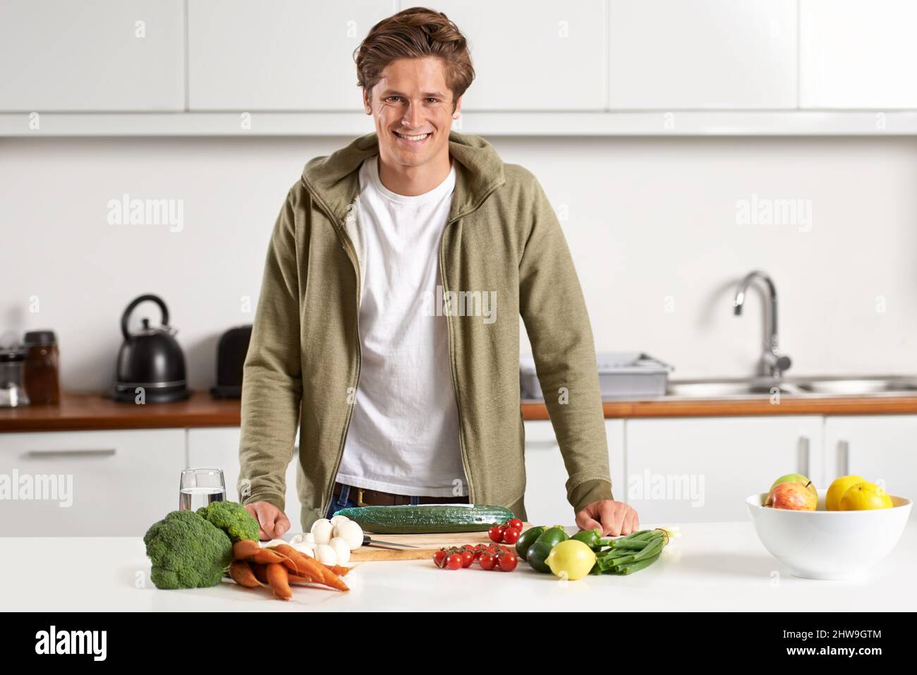 Kochen auf gesunde Art und Weise. Porträt eines jungen Mannes, der das Abendessen vorbereitet. Stockfoto