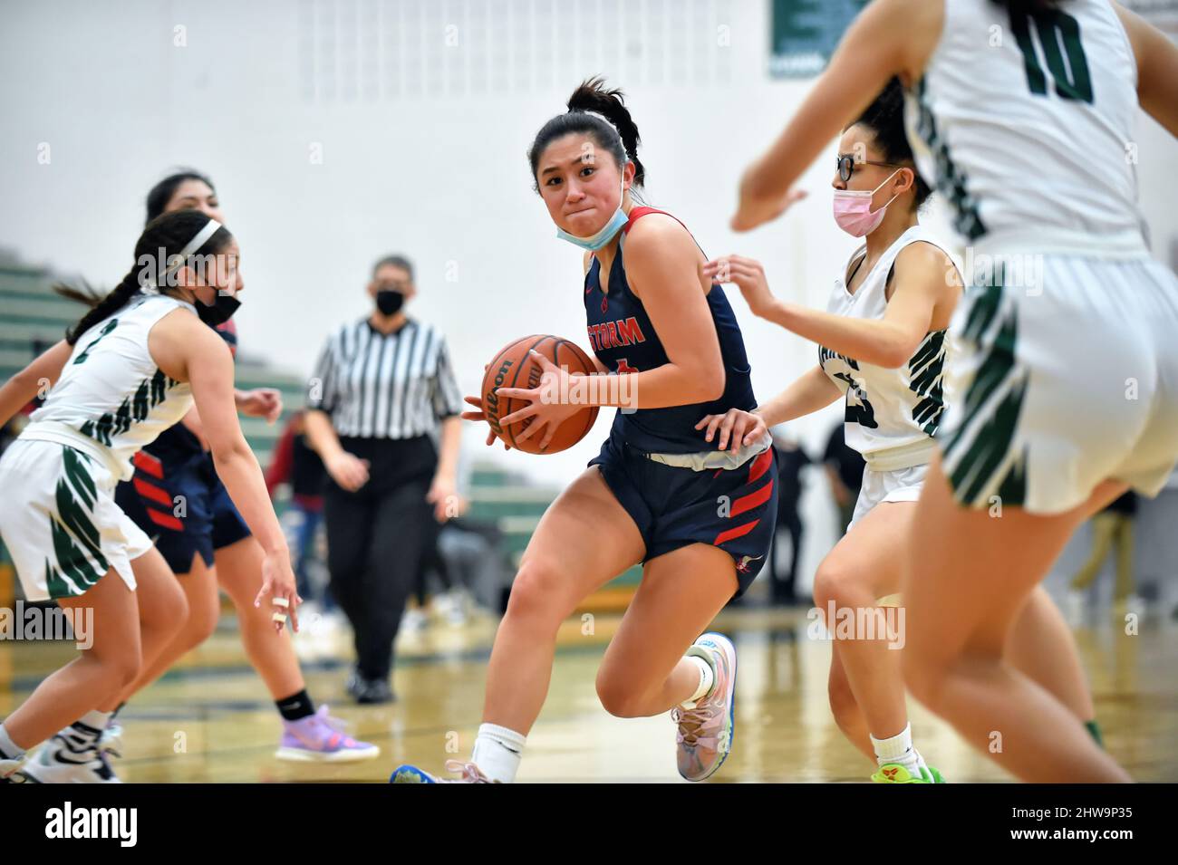 USA. Spieler, der in einem Trio von verteidigenden Gegnern in Richtung Korb fährt. Stockfoto