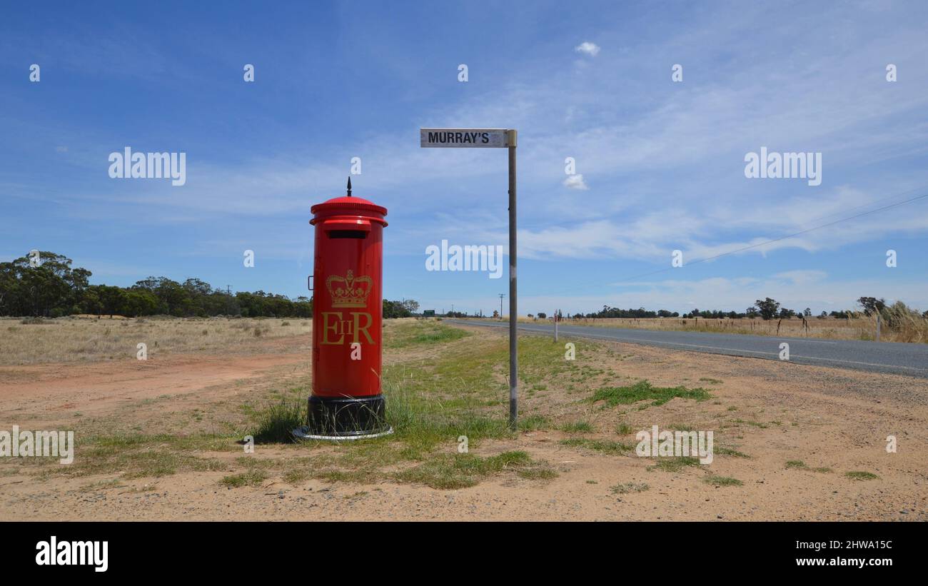 Ein britischer Briefkasten macht einen ungewöhnlichen Briefkasten für eine Farm an der Ecke auf einer abgelegenen und leeren Straße im Outback Australien Stockfoto