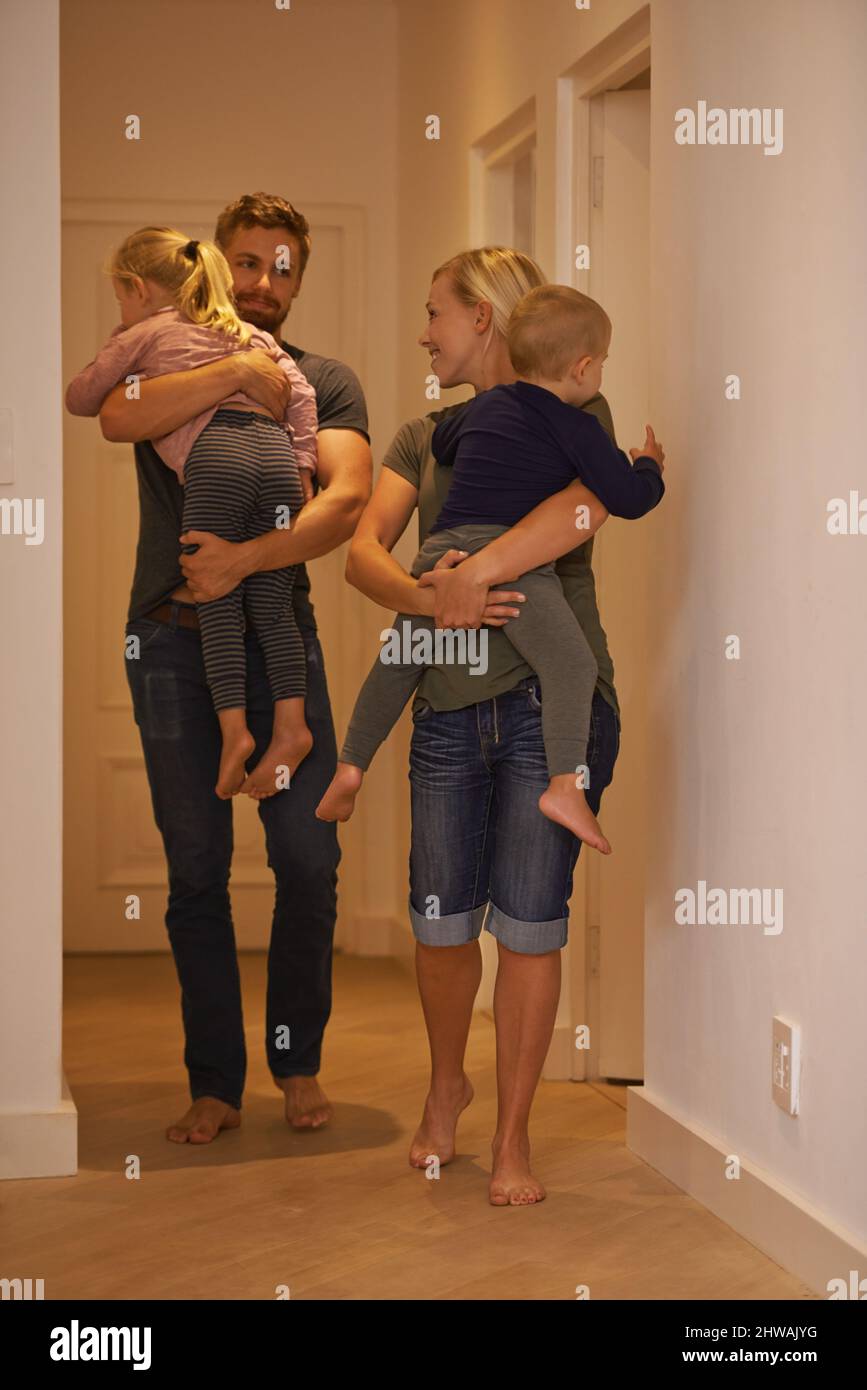 Zeit, diese beiden ins Bett zu bringen. Aufnahme von jungen Eltern, die  ihre schlafenden Kinder ins Bett tragen Stockfotografie - Alamy