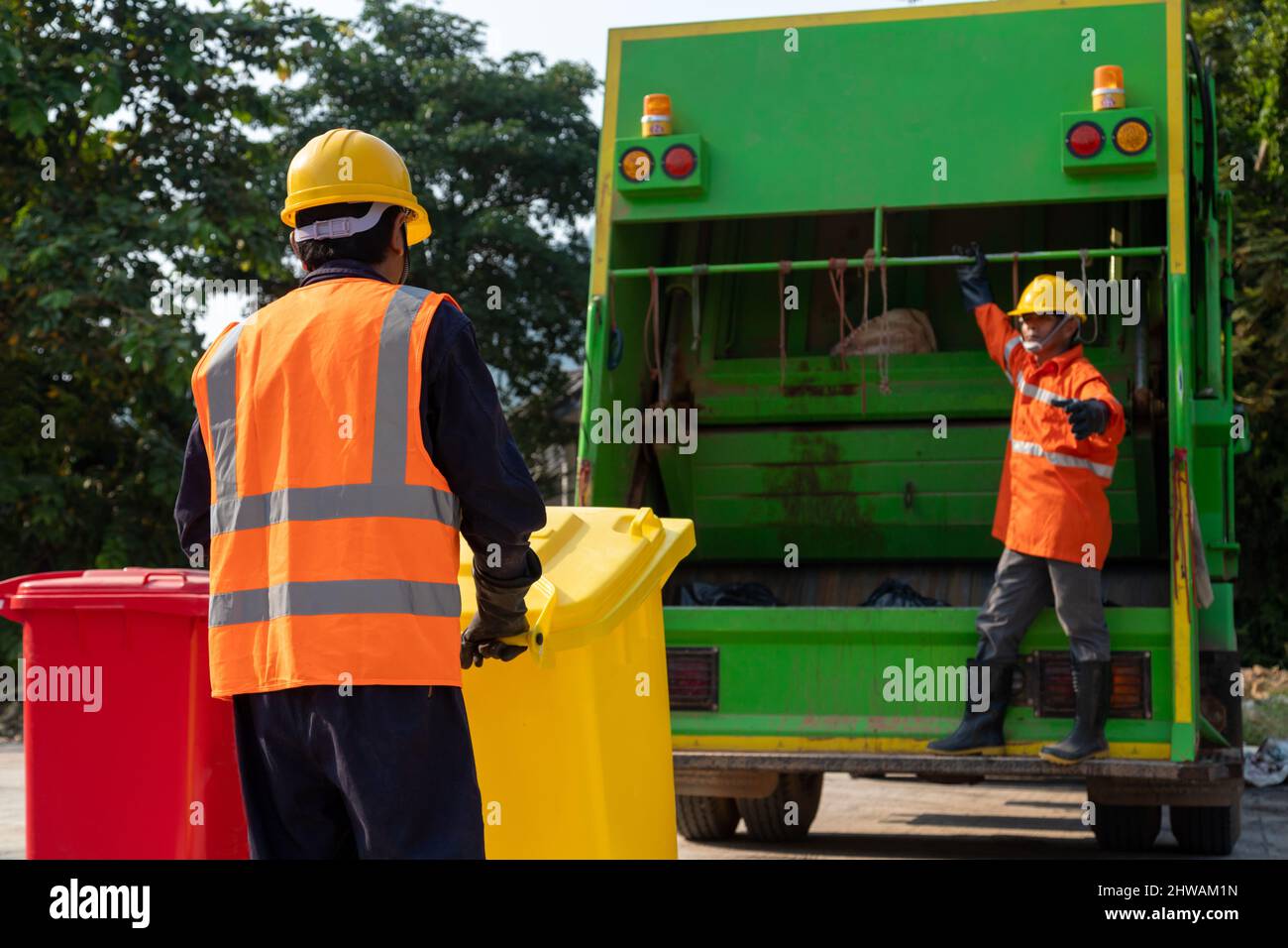 Zwei asiatische Müllmänner arbeiten zusammen daran, die Mülleimer für die Müllentsorgung zu leeren. Garbage Collector. Stockfoto