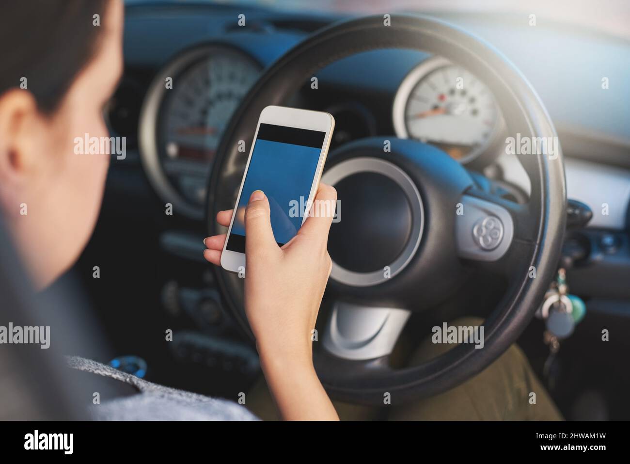 Abgelenkt fahren. Aufnahme einer Frau, die während der Fahrt ein Telefon benutzt. Stockfoto