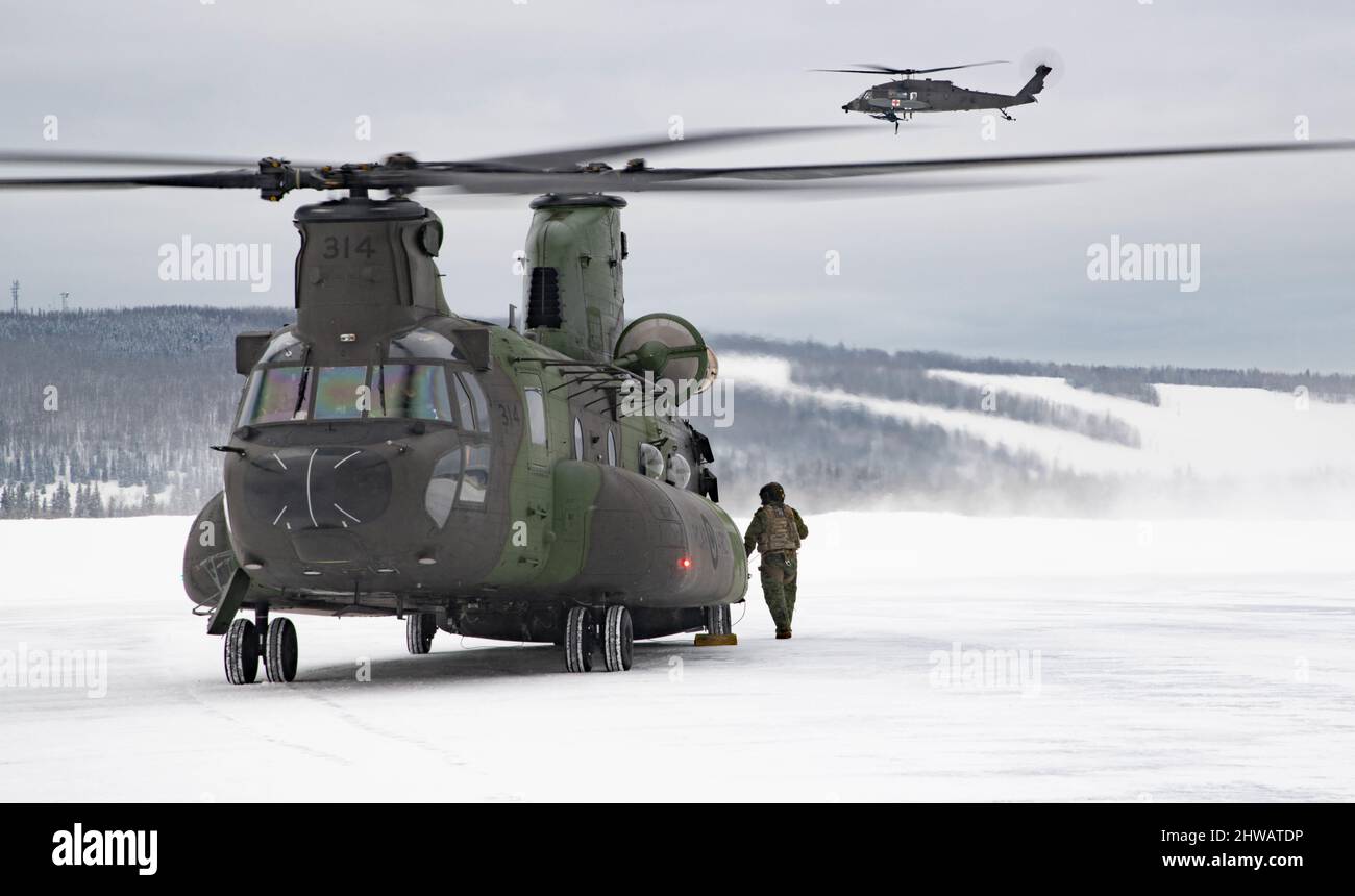 Ein UH-60 Blackhawk schwebt hinter einem CH-147 Chinook bei seiner Ankunft in Alaska für Ex Arctic Warrior 22, in Vorbereitung auf das Joint Pacific Multinal Readiness Center 22-02 in Fort Wainwright, Alaska am 1.. März 2022. Bitte Kredit: Korporal Angela Gore, Canadian Armed Forces Photo Stockfoto