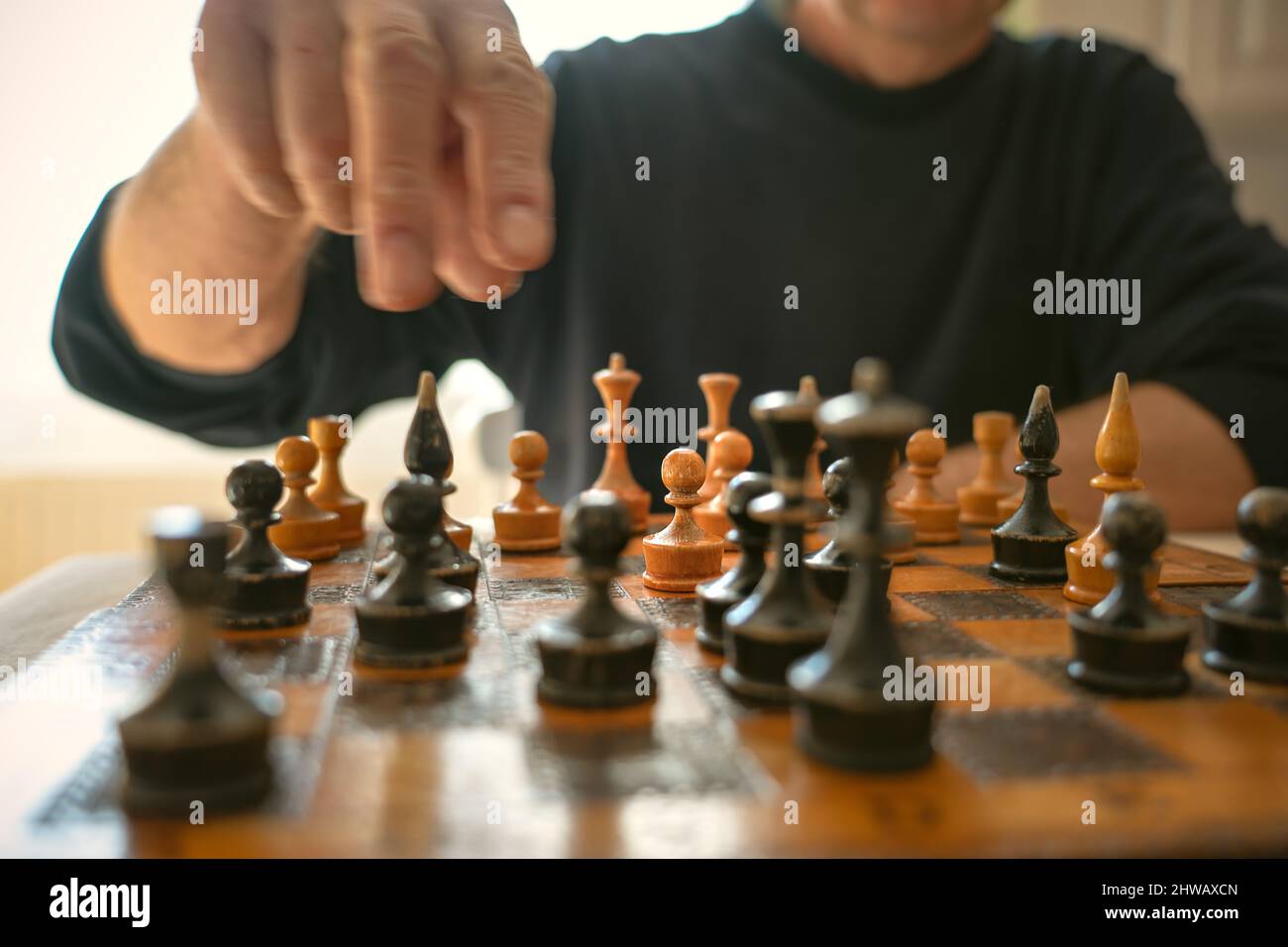 Der verblenkte Spieler spielt seinen nächsten Schritt auf dem alten Schachbrett. Stockfoto