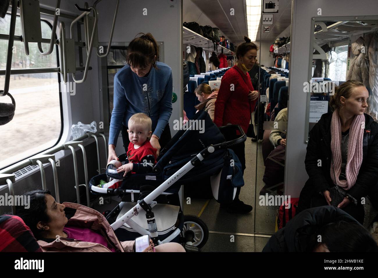 Krakau, Polen. 04. März 2022. Eine Frau sitzt ein Kind in einem Kinderwagen in der Gegend, die den Fahrrädern gewidmet ist, wo Passagiere, die keinen Sitzplatz finden konnten, am 4. März 2022 im Zug zwischen der Grenzstadt Przemysl und der Stadt Krakau im Südosten Polens warten. Foto von Daniel Derajinski / ABACAPRESS.COM Quelle: Abaca Press/Alamy Live News Stockfoto