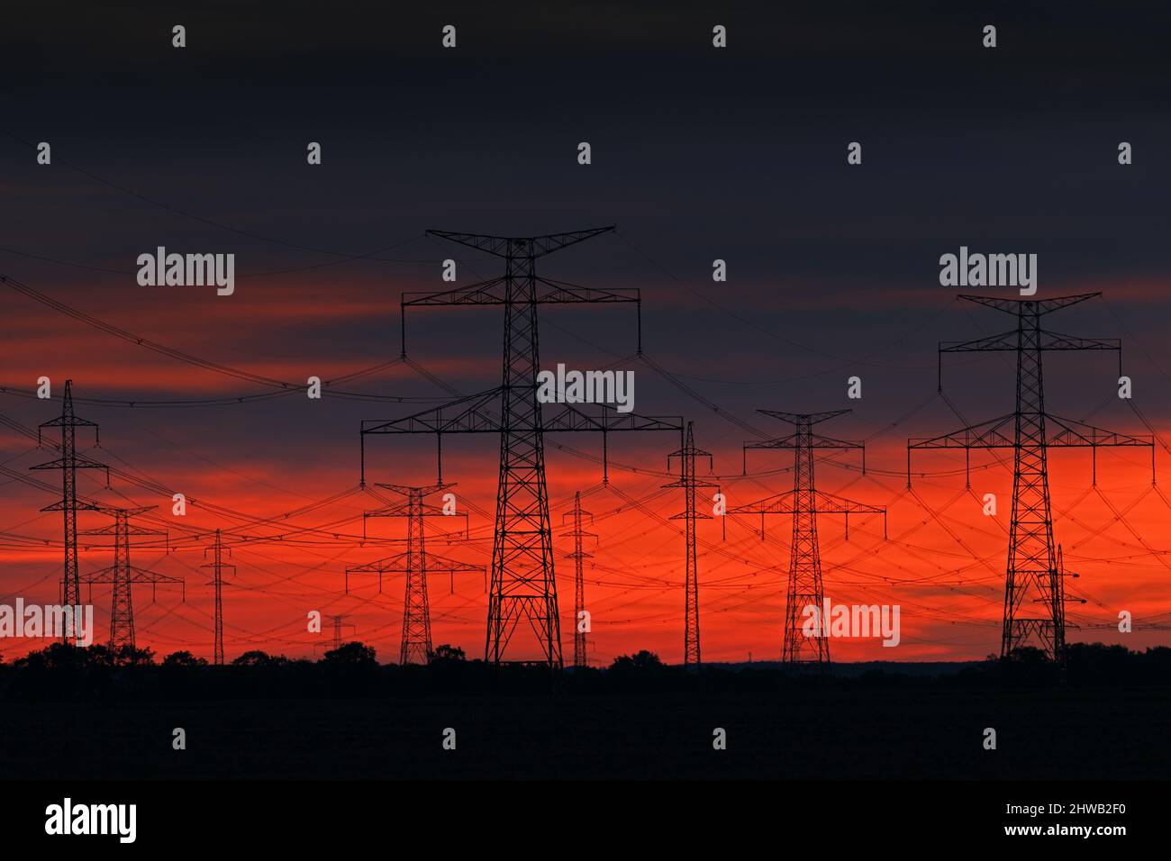 Strommast Sonnenuntergang. Dunkle Nacht mit orangen Wolken Strommasten in der Natur, Tschechische Republik. Energie in der Natur. Sonnenaufgangswolken mit Stangen. Stockfoto