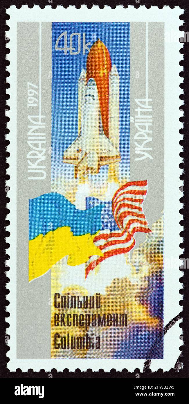 UKRAINE - UM 1997: Eine in der Ukraine gedruckte Marke aus der Ausgabe 'Ukraine-USA Space Flight' zeigt den Start des Space Shuttle Columbia und Flaggen. Stockfoto