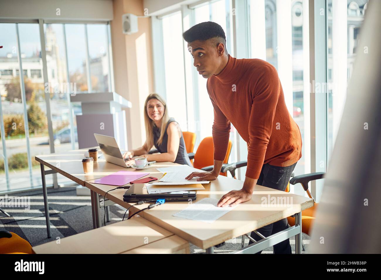 Ein junger Vortragender blickt in einer Arbeitsatmosphäre im Konferenzraum auf die Teilnehmer eines Business-Vortrags. Unternehmen, Mitarbeiter, Unternehmen Stockfoto