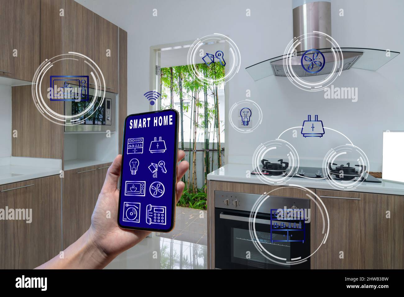 Smart Home- und Augmented Reality-Technologiekonzept, das Smartphone mit der Hand hält und den Smart Home-Bildschirm und das Symbol über der Luxus-Küche präsentiert Stockfoto