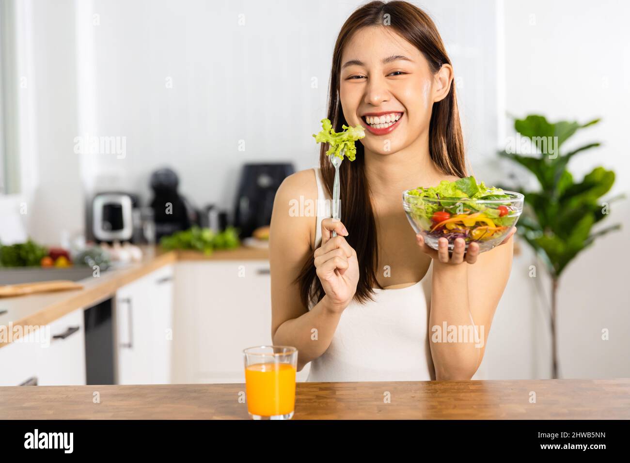 Glückliche asiatische und thailändische Frau essen Salat und Gemüse, Diät und vegetarische Konzept Stockfoto