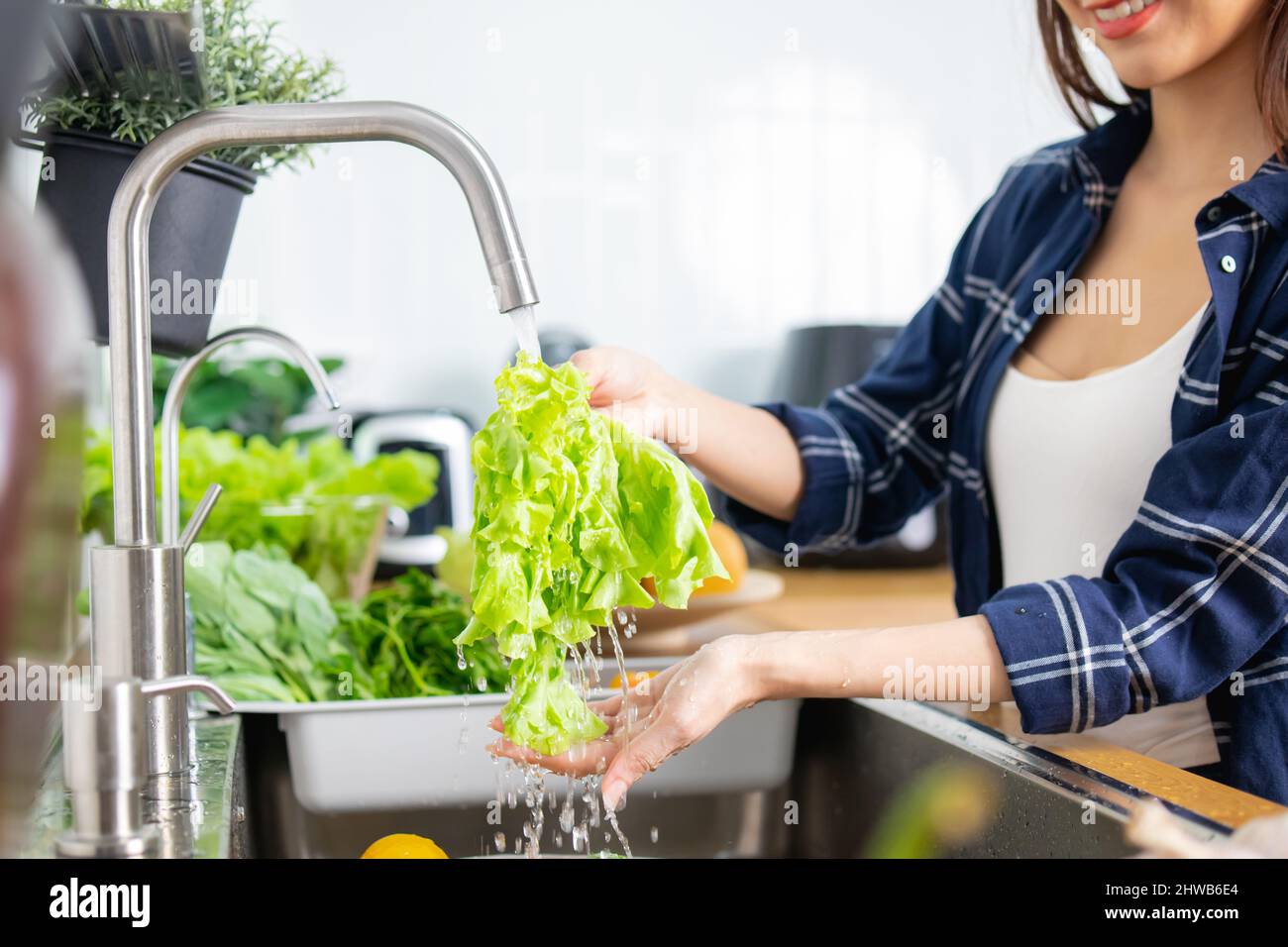 Nahaufnahme Asiatische gesunde Frau, die Gemüse über dem Spülbecken wäscht und Essen zubereitet, Lebensmittel putzt Stockfoto