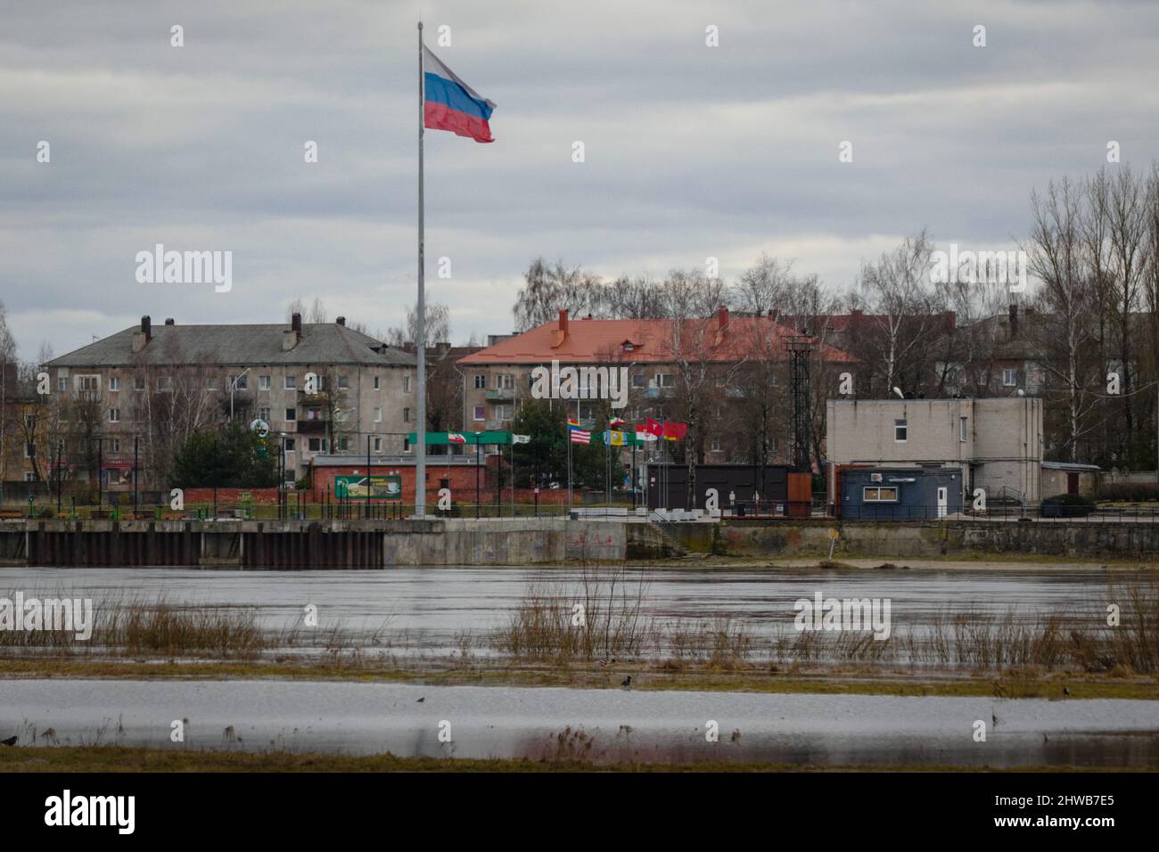 Panemune, Litauen. März 2022. Russische Flagge fliegt in Sovetsk, Kaliningrad über den Fluss Neman von der litauischen Stadt Panemune. Die russische Stadt Sovestck in der russischen Enklave Kaliningrad hat seit der russischen Invasion in die Ukraine wenig Durchgangsverkehr erlebt. Hyperschallraketen, die auf russischem Territorium stationiert sind, haben mehrere europäische Hauptstädte in Reichweite gebracht. Kaliningrad ist vom russischen Festland getrennt und grenzt an Polen, Litauen und die Ostsee BILD: Garyroberts/worldwidefeatures.com Credit: GaryRobertsphotography/Alamy Live Stockfoto