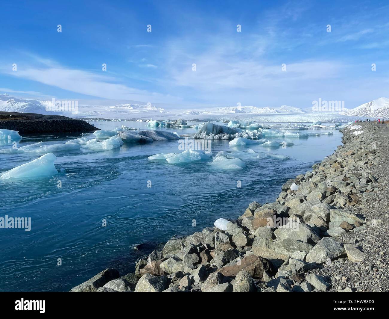 Eisige Küstenlandschaft an einem isländischen Ufer, voll von großen Eisstücken am Strand und schwimmend im Wasser. Stockfoto