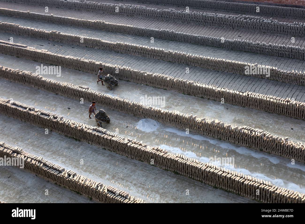 Im Munshigonj District, Bangladesch, arbeiten Arbeiter in einem Ziegelfeld, um Steine zu fertigen. Der Rohstoff des Ziegels ist Ton. Es gibt vier Schritte der Herstellung von Ziegeln. Dies sind die Vorbereitung von Ziegelteinen, das Formen von Ziegelsteinen, das Trocknen von Ziegelsteinen im Sonnenlicht und das Brennen von Ziegelsteinen. Ein Ziegel wiegt 5 Pfund. Normalerweise werden Steine für jede Art von Bauarbeiten verwendet. In diesen Bildern machen Arbeiter Ziegelsteine aus Lehm und trocknen im Sonnenlicht. Nach Abschluss des Trocknungsprozesses werden diese Steine durch Brennen im Feuer hergestellt. (Foto von Syed Mahabubul Kader/Pacific Press) Stockfoto