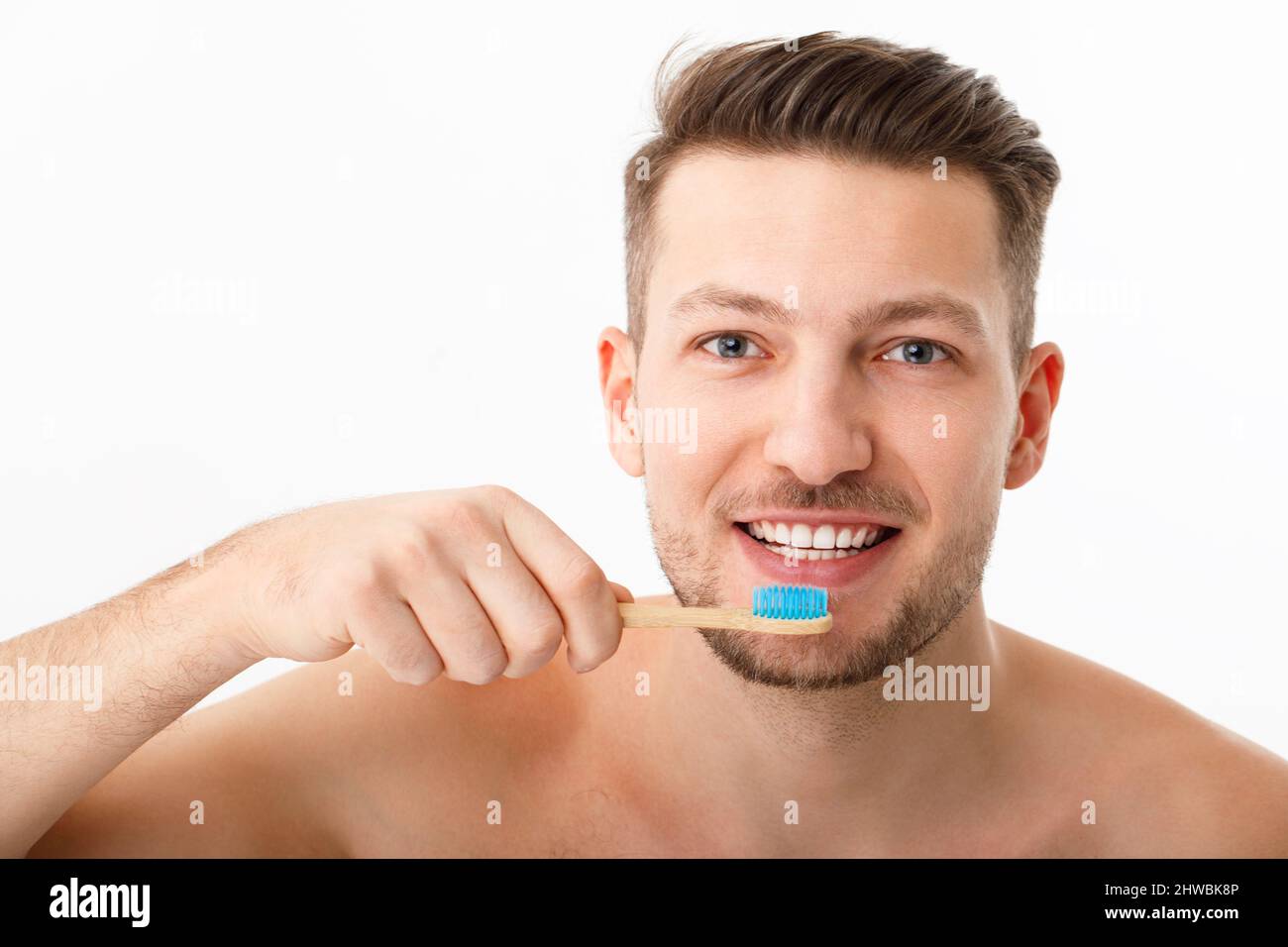 Das Lächeln eines jungen Mannes in Nahaufnahme. Ein Mann hält eine Zahnbürste in der Hand. Das Konzept der Mundpflege. Stockfoto