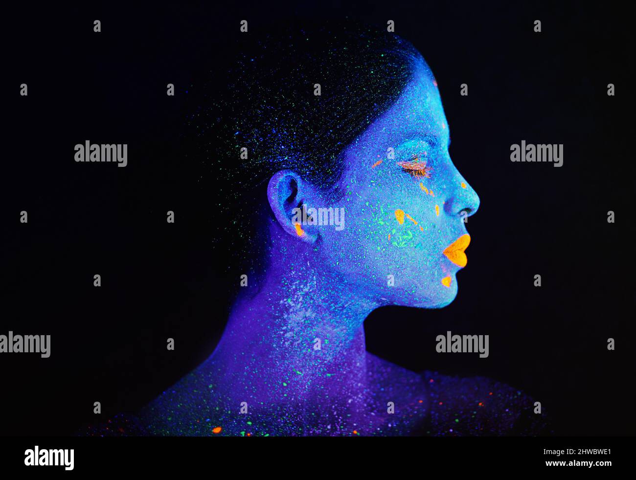 Lassen Sie Ihr Licht erstrahlen. Aufnahme einer jungen Frau, die mit Neonfarbe auf ihrem Gesicht posiert. Stockfoto