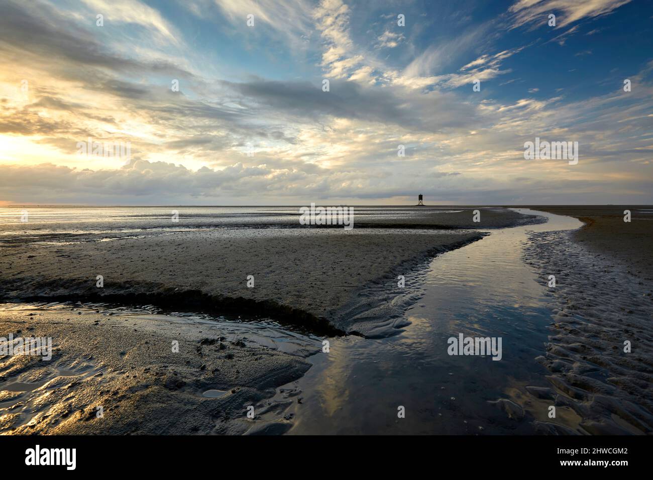 Tideways und ein Leuchtfeuer am Horizont bei Ebbe im Watt nahe der Nordseeinsel Neuwerk. Stockfoto