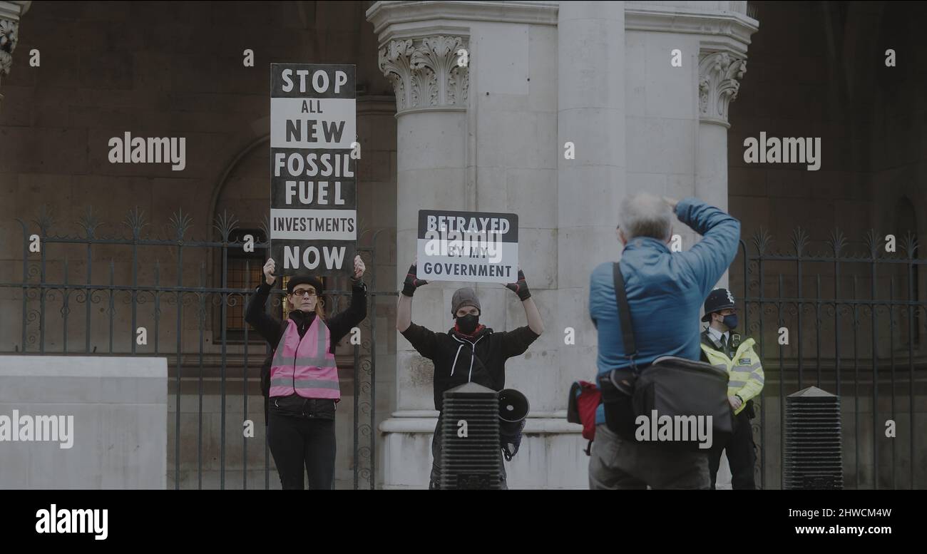 London, Großbritannien - 11 20 2021: Zwei Klimaaktivisten halten Protestschilder vor den Royal Courts of Justice on Strand, für einen beleidigenden britischen Protest. Stockfoto