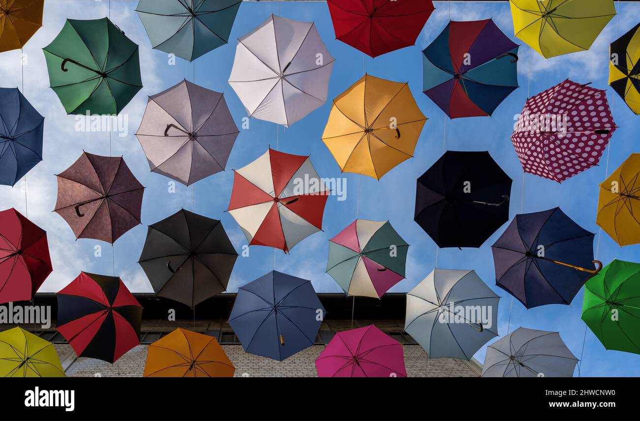 Bunte Regenschirme, die an einer Straße hängen - von unten nach oben Stockfoto