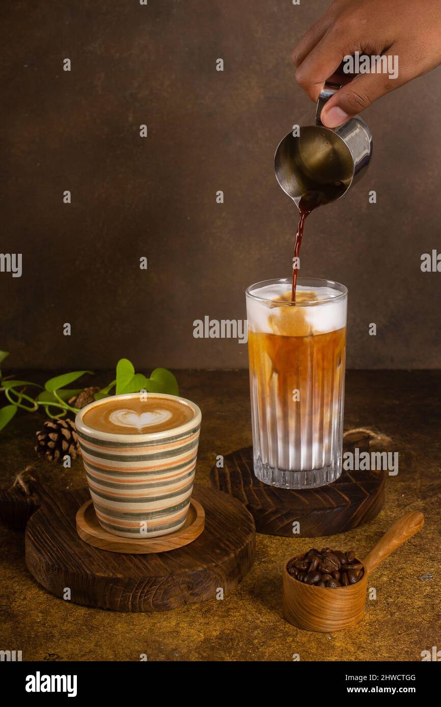 Ein aromatischer Kaffee, der frisch zum Ausgießen gemahlen wird, wird auf einem rustikalen Holztablett zu heißem oder kaltem schwarzen Kaffee Stockfoto
