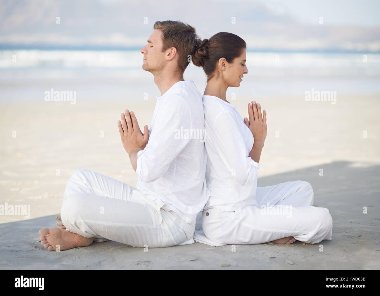 Yoga am Meer. Ein junges Paar, das am Strand Yoga praktiziert. Stockfoto
