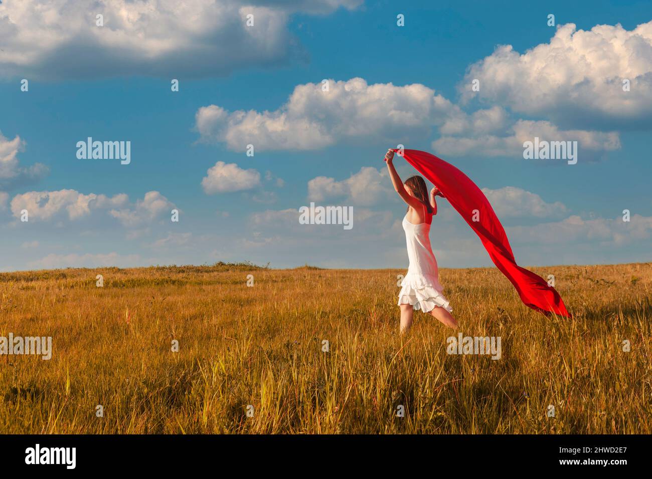 Junge schöne Frau läuft, hält ein rotes Gewebe Stockfoto