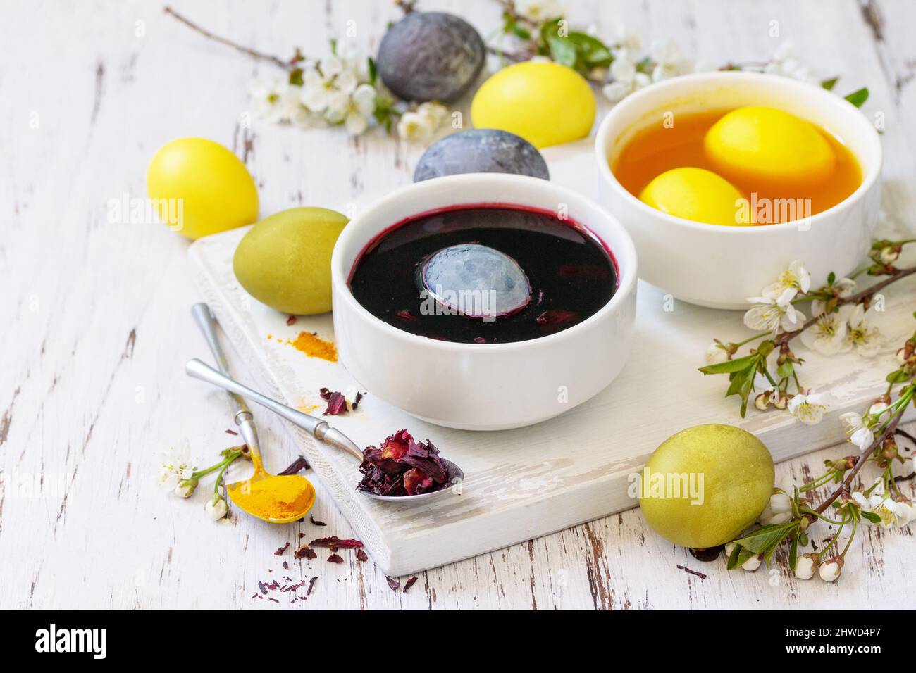 Natürlicher Farbstoff für ostereier, Feier Ostern. Hausgemachte bunte ostereier in Karcade und Kurkuma auf einem rustikalen Tisch. Stockfoto