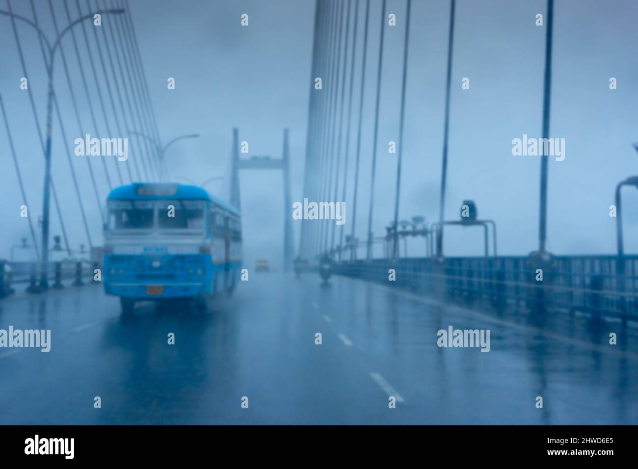 Verschwommenes Bild von Howrah, Westbengalen, Indien. Aufnahme durch Regentropfen, die auf die Windschutzscheibe des Autos fallen, nasses Glas, Verkehr an der Hoogly-Brücke 2.. Stockfoto