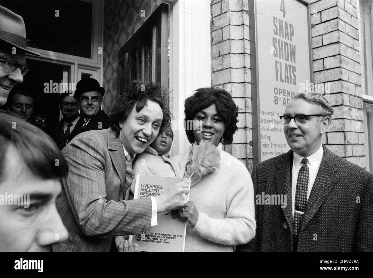 Der Komiker Ken Dodd eröffnet Wohnungen in der Ducie Street und der Beaconsfield Street, Toxteth, Liverpool. Zwei Häuser, eines in jeder Straße, wurden unter einem Team von Schutzhütten- und Planungsexperten zu Wohnungen umgebaut. Ken mit Martha Igbinovia, 23, mit Anthony, 1, und Eve, 2 1/2, einer der Mieter der Wohnungen in der Ducie Street. 7.. April 1970. Stockfoto