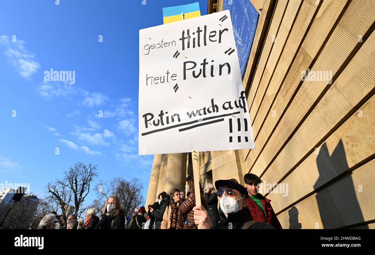 Stuttgart, Deutschland. 05. März 2022. Ein Mann demonstriert mit einem Plakat mit der Aufschrift: "Gestern Hitler heute Putin. Putin wacht auf“ bei einem partizipativen Konzert gegen „Krieg und Gewalt“ der Stuttgarter Philharmoniker, der Staatsoper Stuttgart, des SWR-Symphonieorchesters und des Stuttgarter Kammerorchesters vor dem Opernhaus. Quelle: Bernd Weißbrod/dpa/Alamy Live News Stockfoto